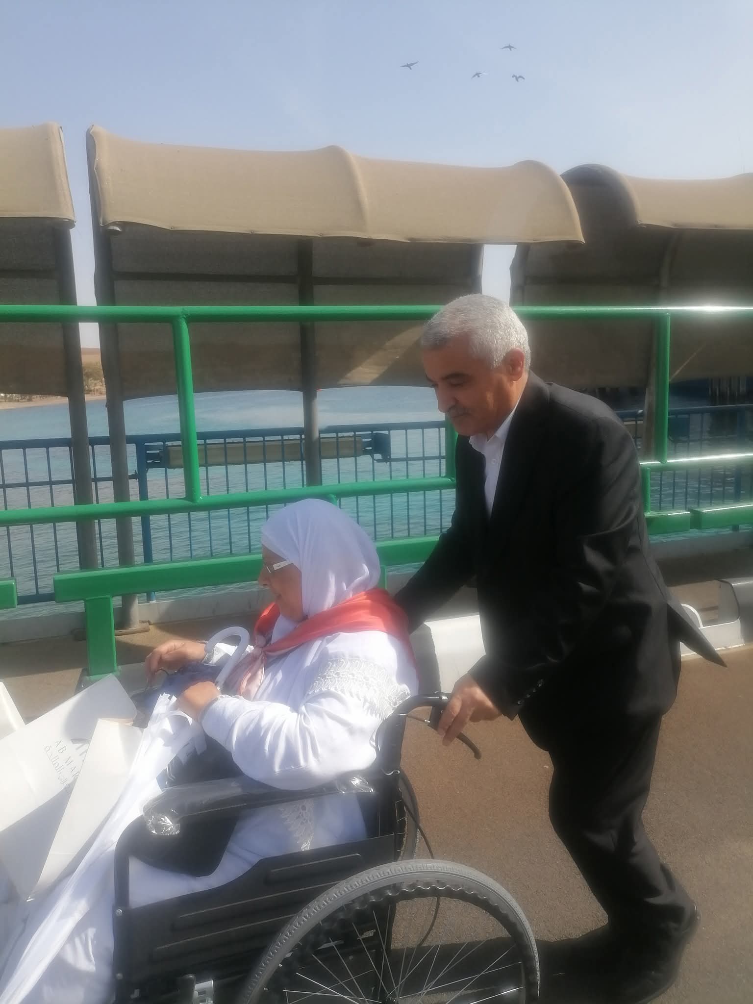 محافظ العقبة خالد الحجاج يدفع عربة حاجة مصرية بعد نزولها من الباخرة في ميناء العقبة